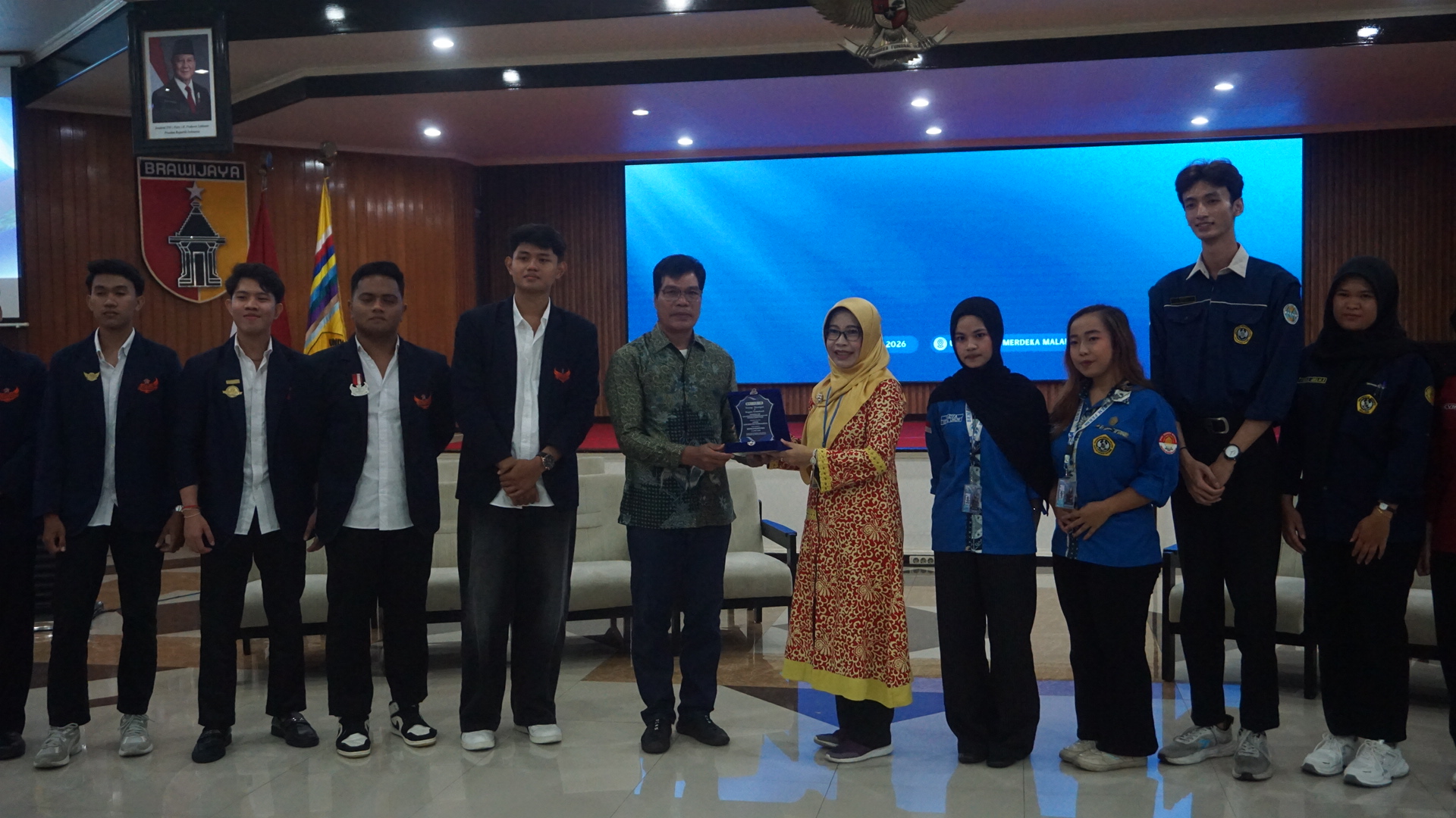 Sesi penukaran cenderamata dari FEB Unmer Malang dan FEB UNWAR Denpasar, oleh Dekan FEB Unmer Malang, Dr. Retna Safriliana, SE., M.Si., Ak., CA (tengah kanan) dan Wakil Dekan III Bidang Kerjasama dan Kemahasiswaan FEB UNWAR Denpasar, I Ketut Selamet, SE., M.Si (tengah kiri), dan didampingi oleh masing-masing organisasi atau lembaga kemahasiswaan FEB dari kedua universitas. 